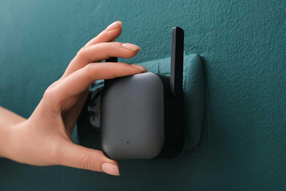 A woman's hand plugging in a WiFi extender to power