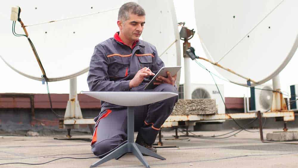A man installing a Starlink satellite dish