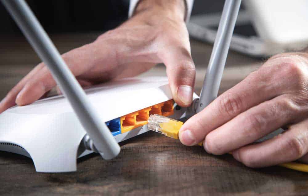 Man Connecting Ethernet Cable to Router
