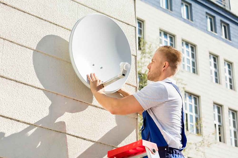 A technician mounting a dish on a wall