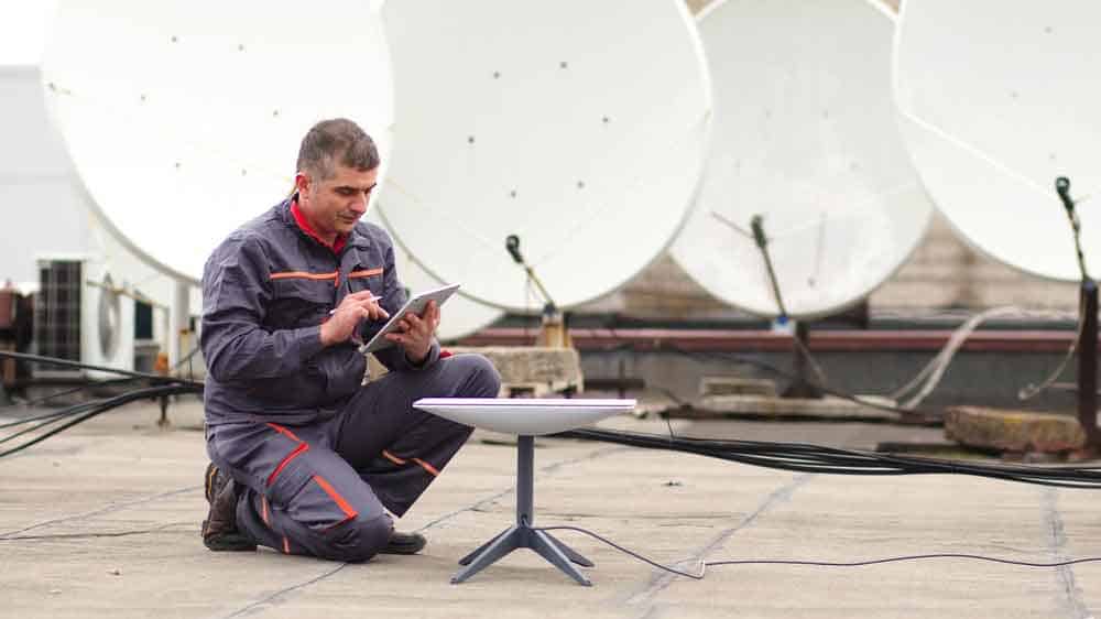 A man installs a Starlink dish for a fast internet connection